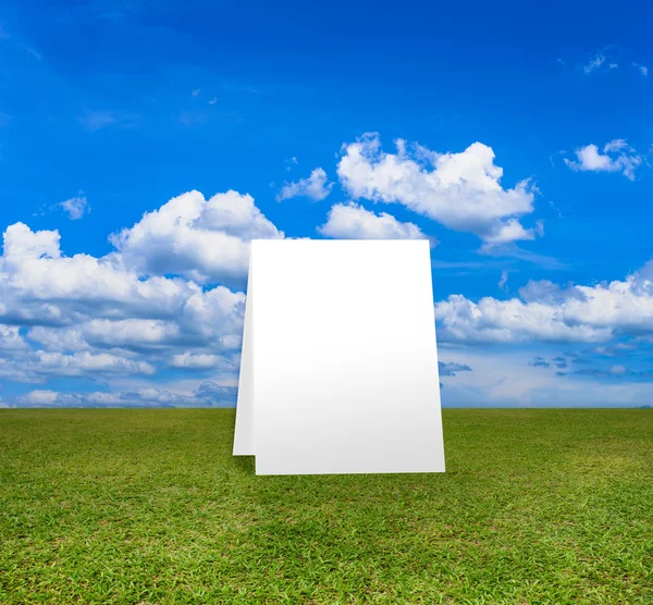 Αφίσα στέκεται στο πράσινο πεδίο κάτω από σύννεφα μπλε ουρανό. — Φωτογραφία Αρχείου