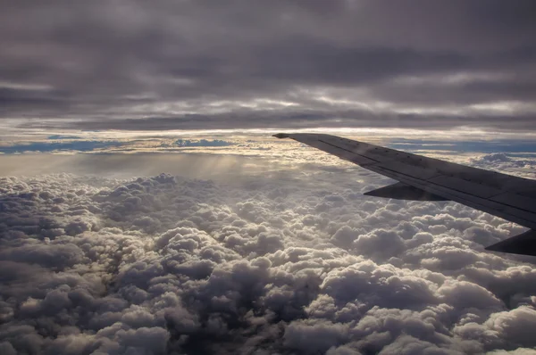 Airplane wing above the clouds from airplane window — Stock Photo, Image