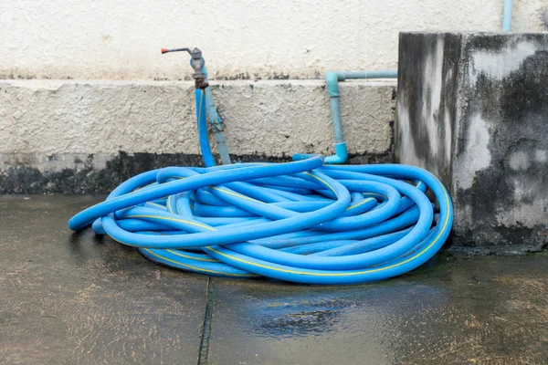 Tube en caoutchouc relié au vieux robinet d'eau sur le sol — Photo