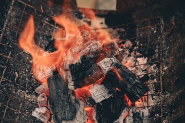 Mangal ızgarasında parlak turuncu alevlerle yanan kömürlere yakın çekim