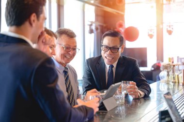 Şirket toplantısında dijital tablet kullanarak strateji ve fikirleri tartışan bir grup iş adamı. Modern bir ofiste takım çalışması, liderlik ve yenilik kavramı