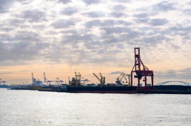Osaka, Japonya 2 Nisan 2025 Osaka Limanı manzarası, Osaka Körfezi 'nde gün batımında büyük vinçli lojistik faaliyetler