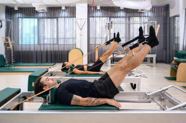 Erkekler ve kadınlar fiziksel sağlığı korumak için kaslarını güçlendirirler. Spor salonundaki pilates derslerini seven bir çift.