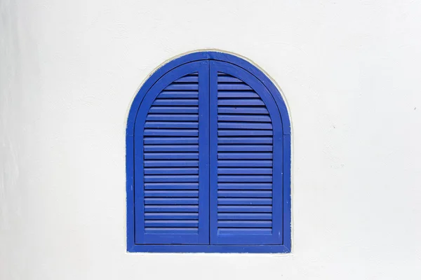 Janela de madeira azul fechada com persianas de madeira na parede de estuque branco — Fotografia de Stock