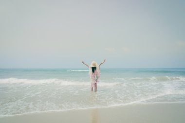 Genç kadın tropik sahilde denize bakarak dinlenmek