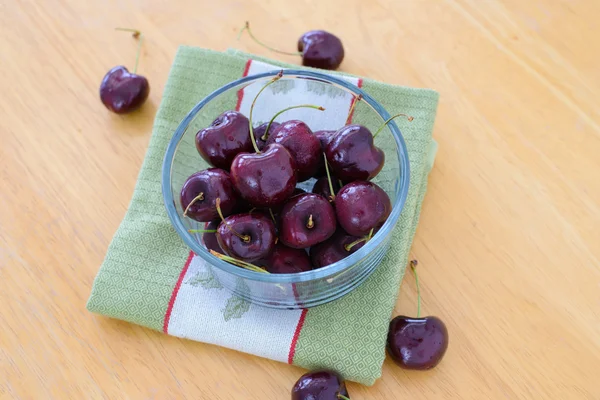 Cerezas en cuenco de vidrio sobre mesa de madera — Foto de Stock