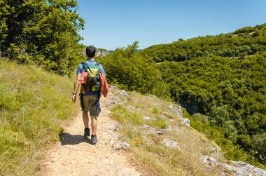 Uzak bir yolda yürüyen sırt çantalı bir adamın arka planı