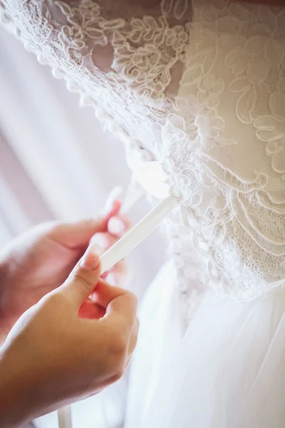 Bridesmaid tying bow on wedding dress — Stock Photo, Image