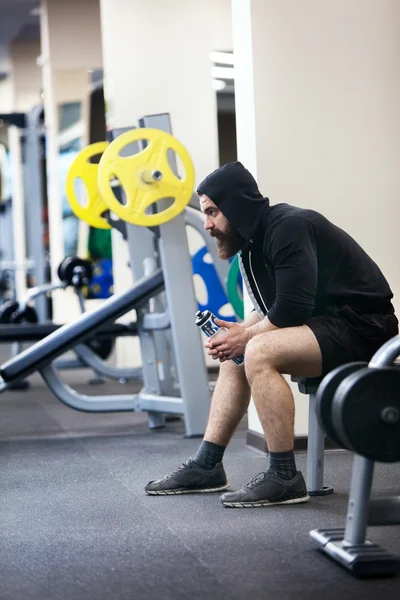 Bodybuilder sitzt auf einem Gewicht — Stockfoto