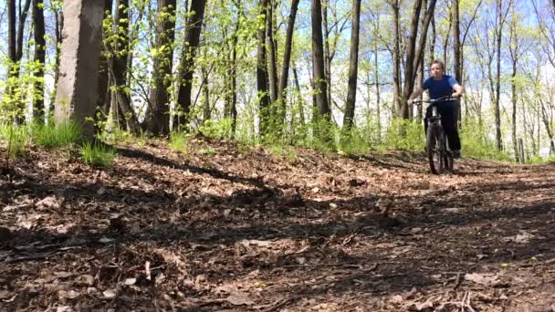 Chico montando rápido una bicicleta en el bosque. Movimiento lento — Vídeos de Stock