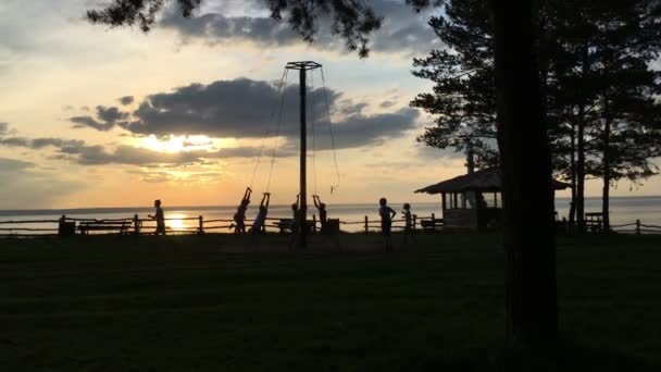 Crianças no pôr do sol passeio em um balanço — Vídeo de Stock