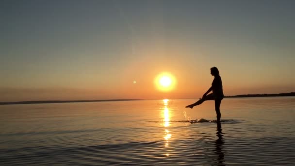 Una giovane ragazza spruzza acqua al tramonto — Video Stock