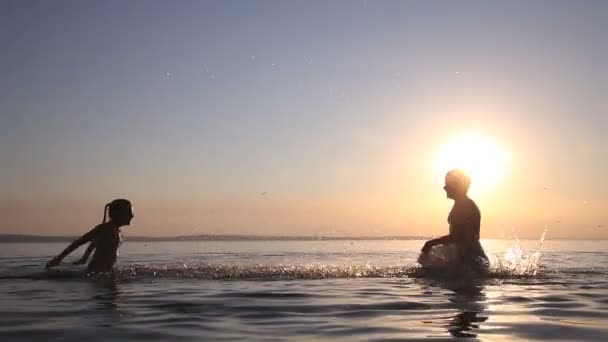 Crianças pulverizam água ao pôr do sol — Vídeo de Stock
