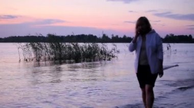 Kız su üzerinde günbatımında yürür.