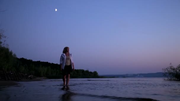 Menina caminha na água ao pôr do sol — Vídeo de Stock