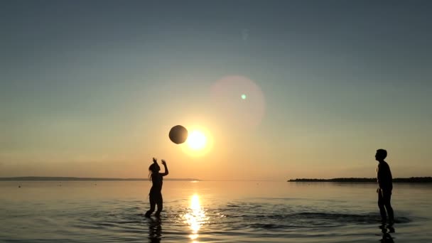 Niños jugando pelota en el agua al atardecer . — Vídeo de stock