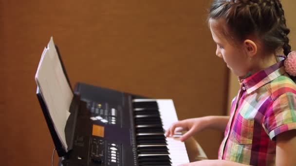 Mladá dívka si hraje na syntezátor — Stock video