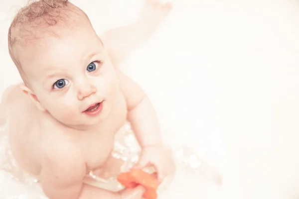 Cheerful baby looking up at camera while playing in bath — Stock Photo, Image