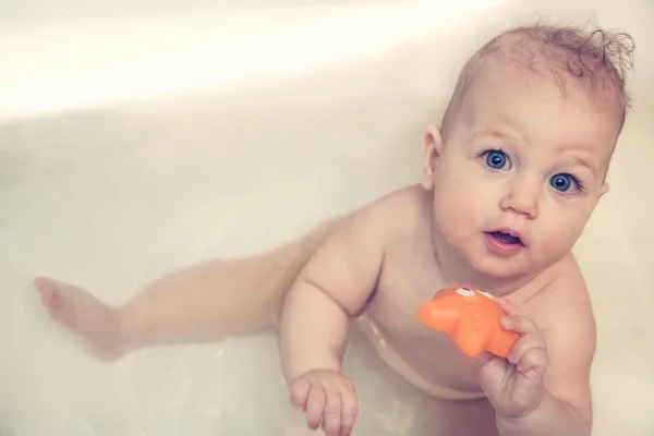 Cheerful baby looking up at camera while playing in bath — Stock Photo, Image
