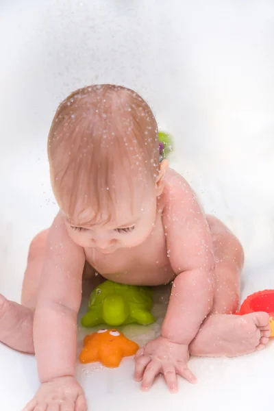 Baby playing with toys in bathroom during shower — Stock Photo, Image