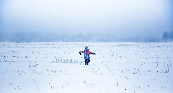 Liten flicka kör bort i en snöig park — Stockfoto