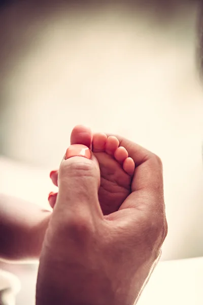 Pies de bebé en las manos de la madre — Foto de Stock