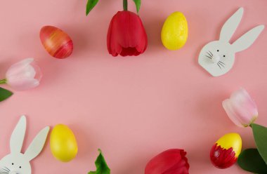 Laleler, Paskalya yumurtaları, pembe arka planda tahta tavşanlar. Tasarım için arka plan. Paskalya tasarımı. Boşluğu kopyala.