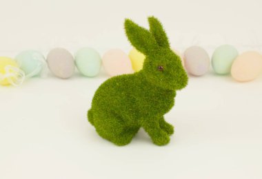 Renkli dekoratif yumurtalardan oluşan arka planda yeşil paskalya tavşanı. Şenlik arka planı. Mutlu Paskalyalar. Metin için yer.