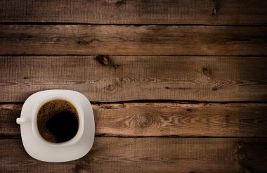 Black coffee rests in a white cup on a wooden surface.