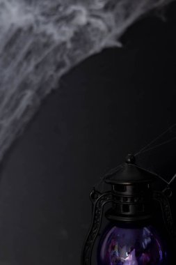 Lantern casts a glow on cobwebs in a dark room.