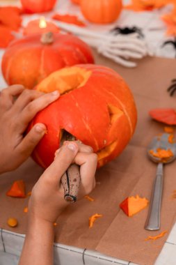 Cadılar Bayramı kutlaması için iki el ustaca balkabağı oyuyor..