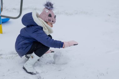 Kışın giyinmiş küçük bir çocuk karda akıllı bir telefonla etkileşime girer..