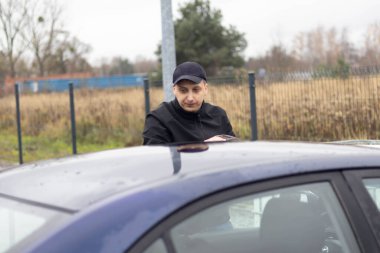 Bir adam, dışarıdaki bir araba yıkamada yıkadıktan sonra aracını havluyla siler..