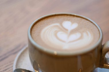 İki kalbi gösteren bir fincan, yakınlarda bir kaşıkla ahşap bir yüzeye yerleştirilir..