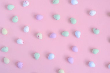 Dekorasyon için pembe bir yüzeye yerleştirilmiş farklı renklerde küçük şekerler.