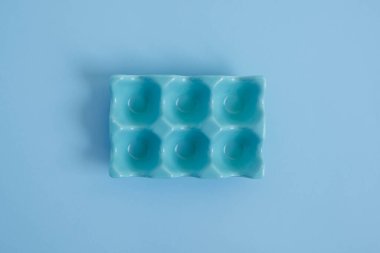 Paskalya hazırlıkları için mavi arka plana yerleştirilmiş basit bir yumurta tutucu..