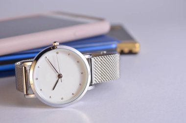 Kadın saati, telefon, flaş bellek ve not defteri masada..