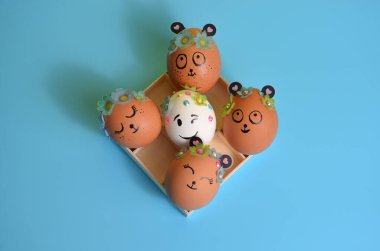 Mavi arka plandaki bir kutuda boyalı ağızlıkları olan paskalya yumurtaları. Paskalya.