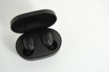 Beyaz arka planda küçük kablosuz kulaklıklar.