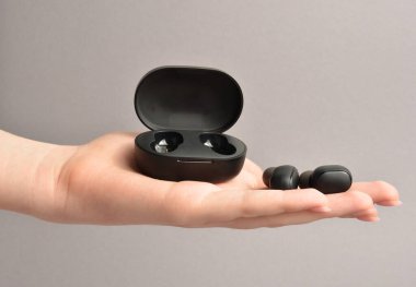 Avucundaki kablosuz kulaklıklar. Gri arkaplan.