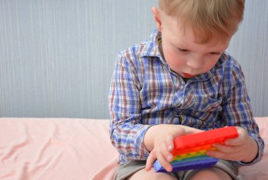 Küçük bir çocuk bir oyuncakla oynuyor. Patlat şunu.