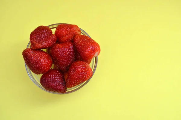 Erdbeeren in einer Schüssel auf gelbem Hintergrund. — Stockfoto