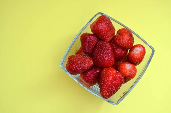 Erdbeeren in einer Glasschale auf gelbem Hintergrund. — Stockfoto