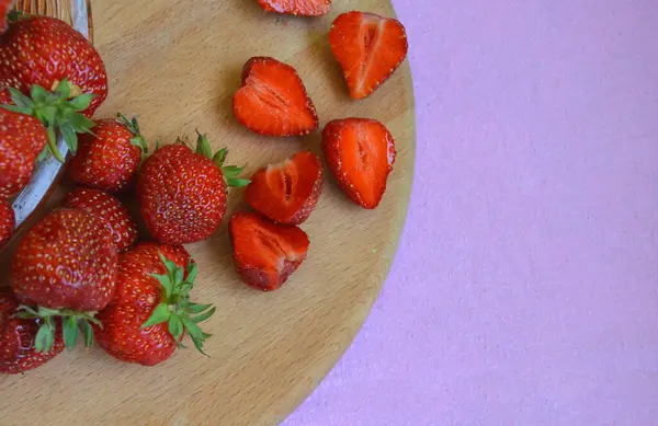 Frische Erdbeeren und Erdbeerscheiben auf einem Holzbrett. — Stockfoto