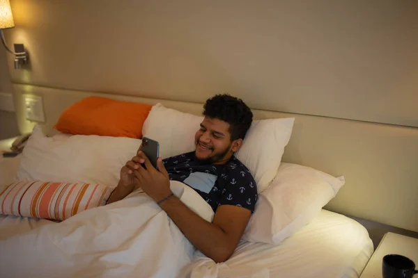 Man Met Behulp Van Mobiele Telefoon Liggend Bed Met Kopje — Stockfoto