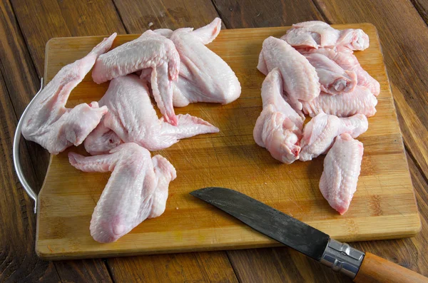 Rohe Hühnerflügel mit Messer auf Holz — Stockfoto