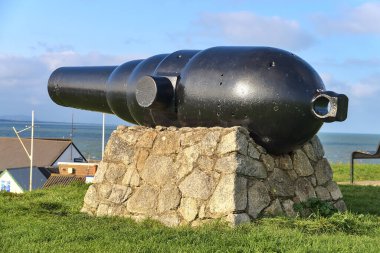 Black Castle, South Quay, Corporation Lands, Co. Wicklow, İrlanda 'daki çimenli bölgede taş standında duran eski dev siyah top. Eski ve eski silahlar.