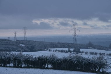 Ticknock, Dublin, İrlanda 'da koyu gri gökyüzüne karşı yüksek voltajlı elektrik hatlarıyla çekilen güzel sıradışı İrlanda kış manzarası