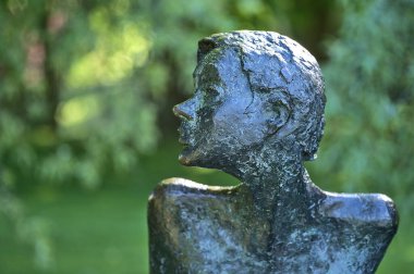 Dublin, İrlanda - 30 Nisan 2021: Üniversite Üniversitesi Dublin 'deki Buluşma Heykeli' nin UCD Gölü 'nün yanında çeşitli yeşil bahar renklerinde güzel yakın plan görüntüsü. Kürsüde oturan kadın heykeli