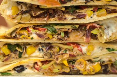 Tatlı mısır, avokado, kırmızı soğan, kırmızı biber ve ahşap servis tahtasının üzerinde kişniş bulunan lezzetli siyah fasulyeli Meksika quesadillaları. Quesadilla arkaplanı